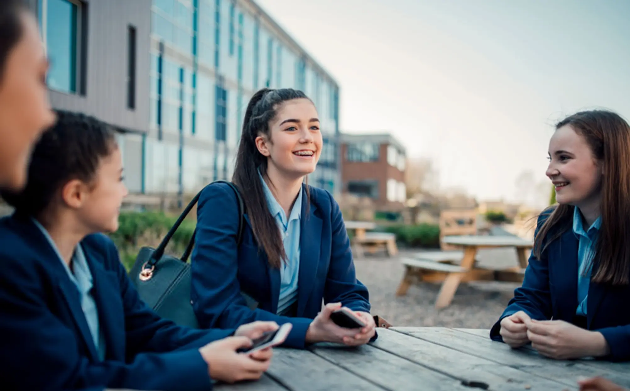 Three students sitting outdoors and chatting